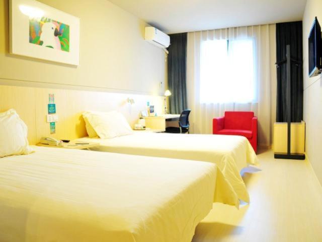 a hotel room with two beds and a red chair at Jinjiang Inn Suzhou Railway Station Huqiu in Suzhou