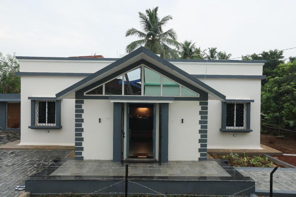 een wit huis met een palmboom op de achtergrond bij Basaghara On Chilika - A Bungalow in Mangalajodi in Jāmb