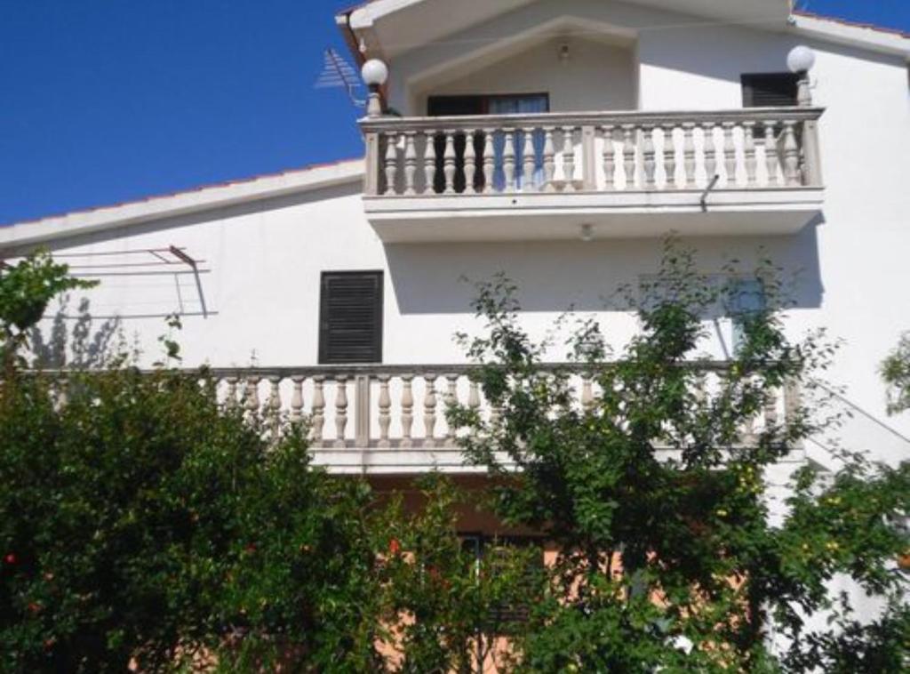 a white building with a balcony on the side of it at Apartments Miki Rogoznica in Podglavica