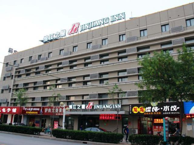 a large building with a sign on top of it at Jinjiang Inn Cangzhou Railway Station in Cangzhou