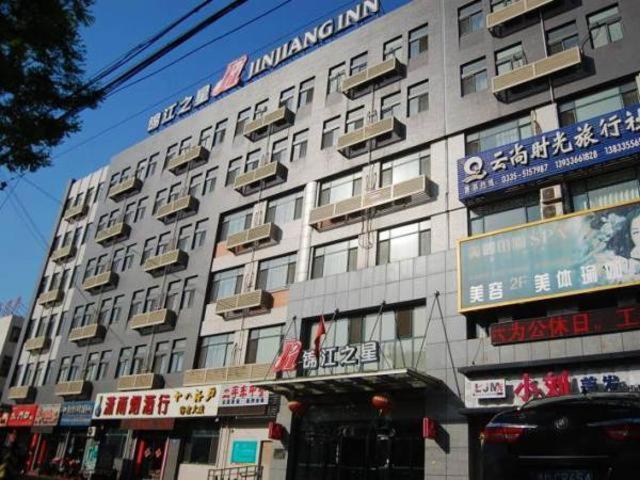 un gran edificio con letreros en el costado en Jinjiang Inn Qinhuangdao Shanhaiguan Railway Station Laolongtou Road Hotel, en Dongzhuang