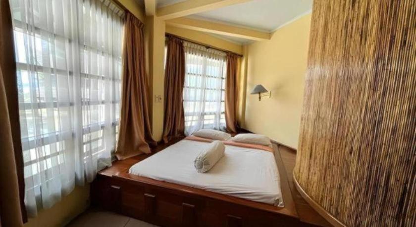 una cama en una habitación con una ventana grande en Sapadia Hotel Parapat, en Parapat