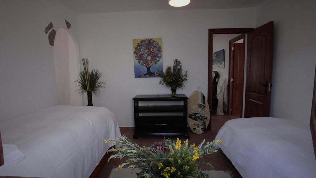 a bedroom with two beds and a table with flowers at Casa Entre Armonías in Zahara de los Atunes