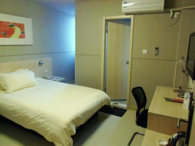 a bedroom with a bed and a desk and a chair at Jinjiang Inn Rudong Qingyuan Road in Rudong