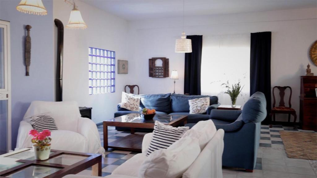 a living room with a blue couch and white chairs at Casa Entre Armonías in Zahara de los Atunes