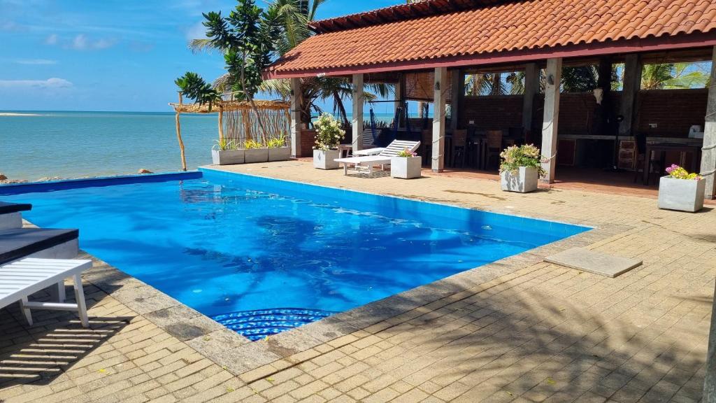 a swimming pool in front of a house with the ocean at Wellé Wadiya Beach Villa in Kalpitiya