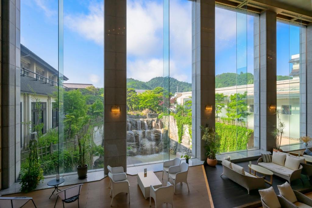 un grand hall d'entrée avec de grandes fenêtres et une cascade dans l'établissement Tendo Hotel, à Tendō