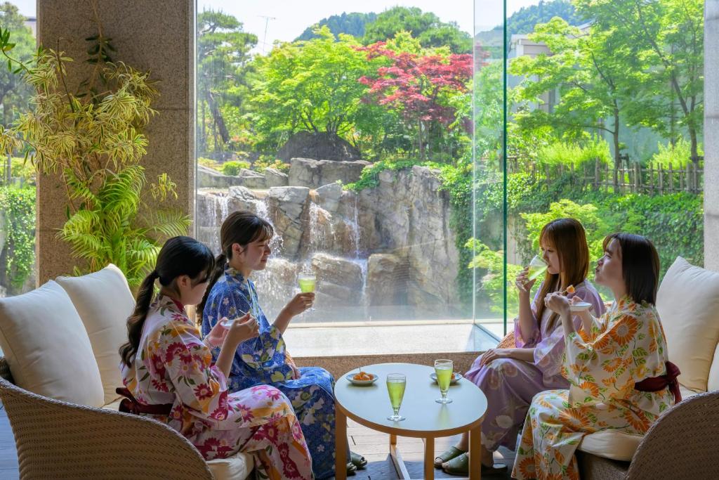 um grupo de pessoas sentadas à volta de uma mesa com bebidas em Tendo Hotel em Tendo
