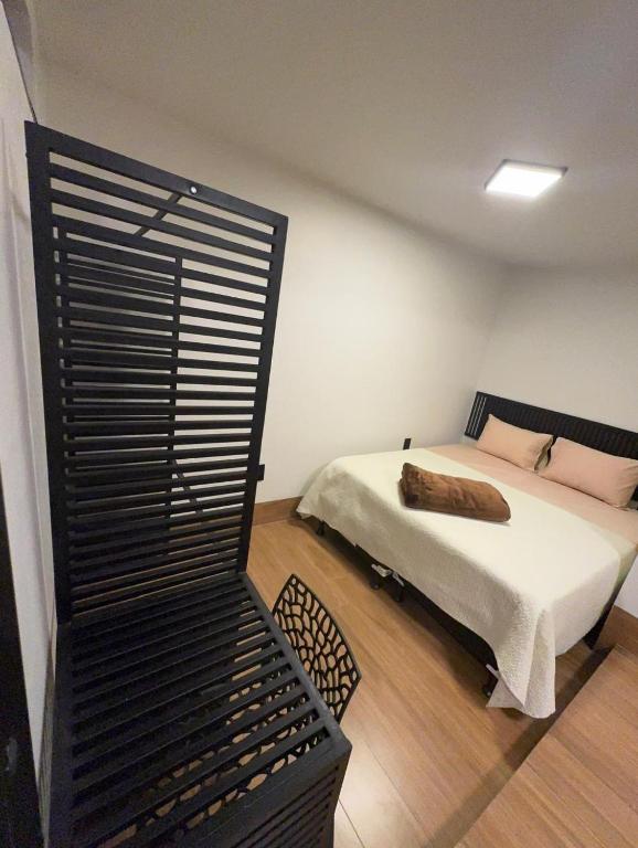 a bedroom with a bed with white sheets and pink pillows at 4Kitnet nova no centro in Lavras