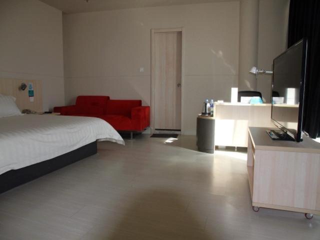 - une chambre avec un lit et un canapé rouge dans l'établissement Jinjiang Inn Zhangjiakou Xuanhua People's Park, à Zhangjiakou