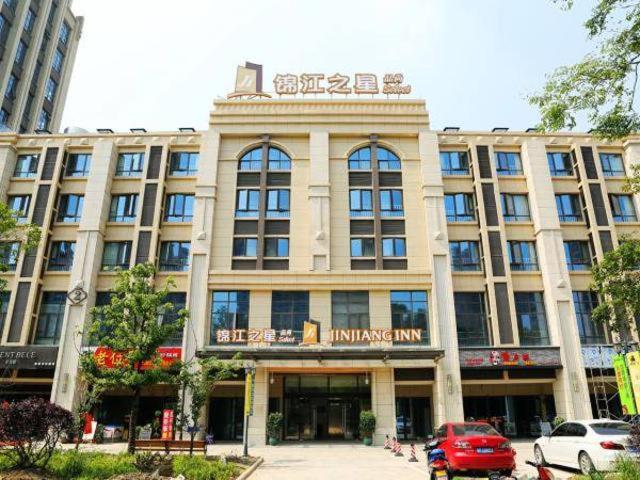 een groot gebouw met auto's geparkeerd voor het bij Jinjiang Inn Select Suzhou Industrial Zone Jundi Manhattan Plaza in Suzhou