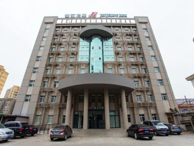 un gran edificio con coches estacionados frente a él en Jinjiang Inn Lianyungang Donghai Town Heping Middel Road, en Donghai