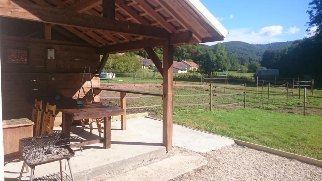 een houten paviljoen met een picknicktafel en een veld bij Gîte du Plainet in Ronchamp