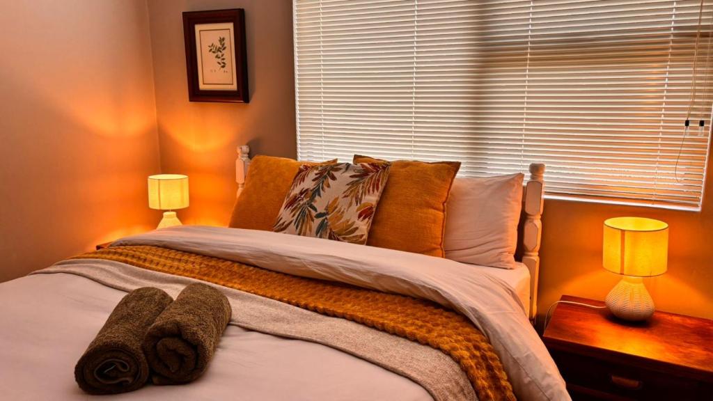 ein Schlafzimmer mit einem Bett mit zwei Lampen und einem Fenster in der Unterkunft Searle Cottage in George