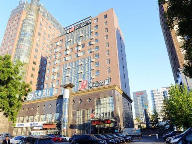 a large building with cars parked in a parking lot at Jinjiang Inn Langfang Wanda Plaza in Langfang