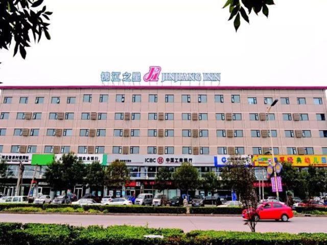 un gran edificio con un coche rojo delante de él en Jinjiang Inn Bazhou Shengfang Town, en Bazhou