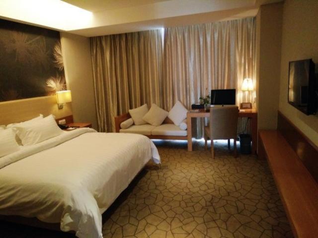a hotel room with a large bed and a couch at Metropolo, Jinjiang, Wanda Plaza in Jinjiang
