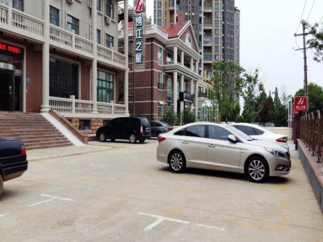two cars parked in a parking lot in a city at Jinjiang Inn Yantai Binhai Road Haiyun Road in Yantai