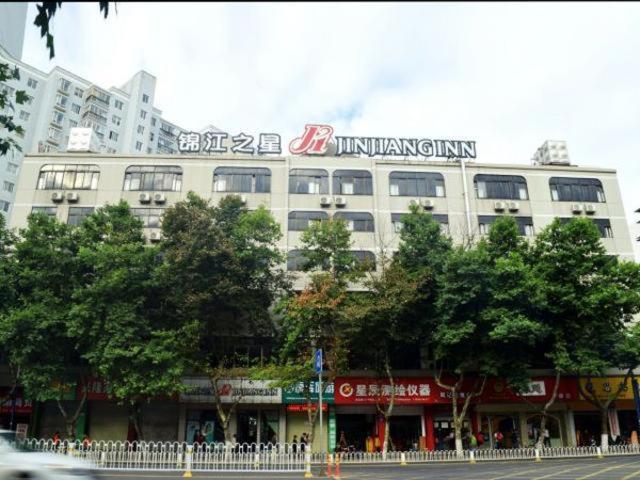een wit gebouw met een bord erop bij Jinjiang Inn Kunming Xichang Road Jinma Biji Historic Site in Kunming