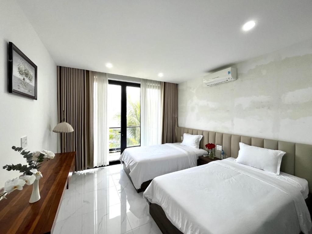a hotel room with two beds and a window at Biệt thự nghỉ dưỡng Saint Simeon Long Hải in Ấp Phước Tĩnh