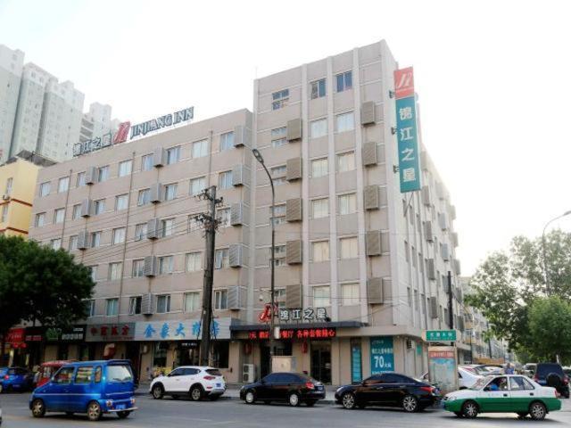 een groot gebouw met auto's geparkeerd voor het bij Jinjiang Inn Hengshui Railway Station in Hengshui