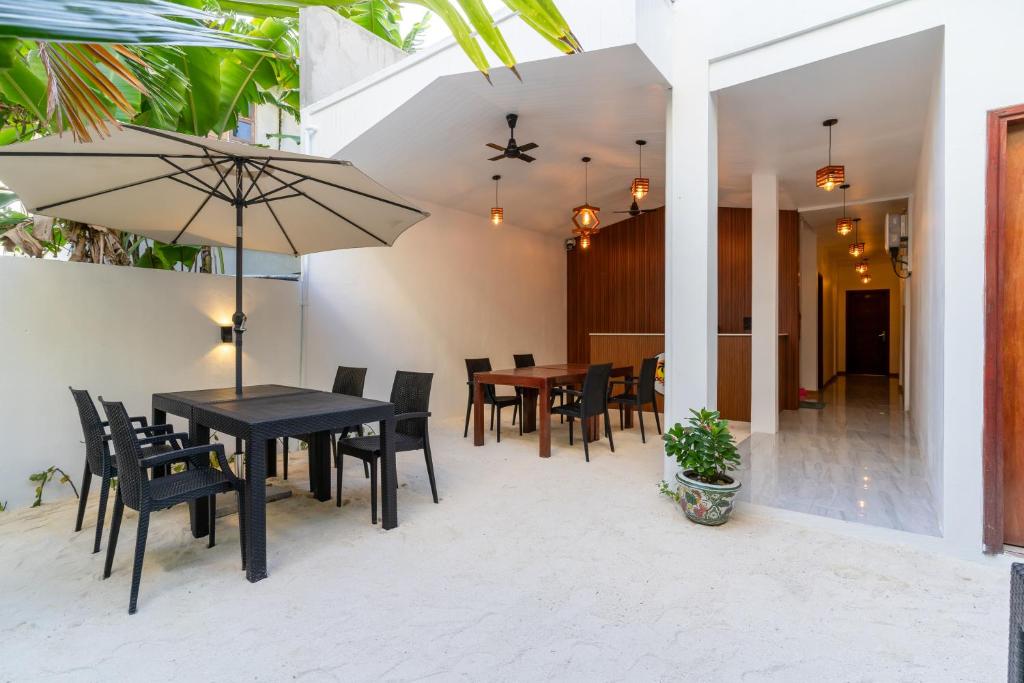 a dining room with a table and chairs and an umbrella at Coco Ukulhas Villa in Ukulhas