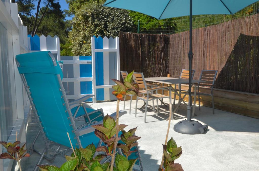 a patio with an umbrella and a table and chairs at Maisonnette Gatseau in Saint-Trojan-les-Bains