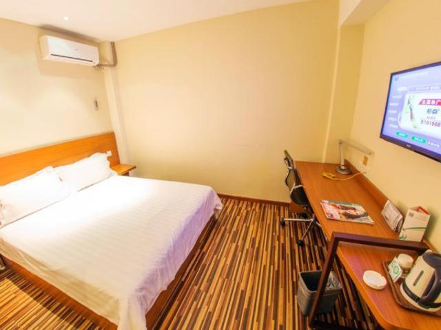 a bedroom with a bed and a desk with a television at Jinjiang Inn Select Weihai South Haibin Road Haishang Park in Weihai