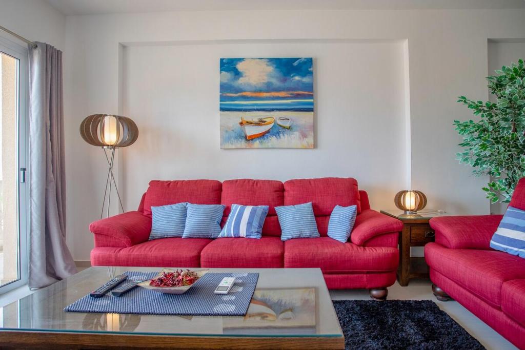 a living room with a red couch and a table at Tranquil hideaway with breathtaking sea views in Kissonerga