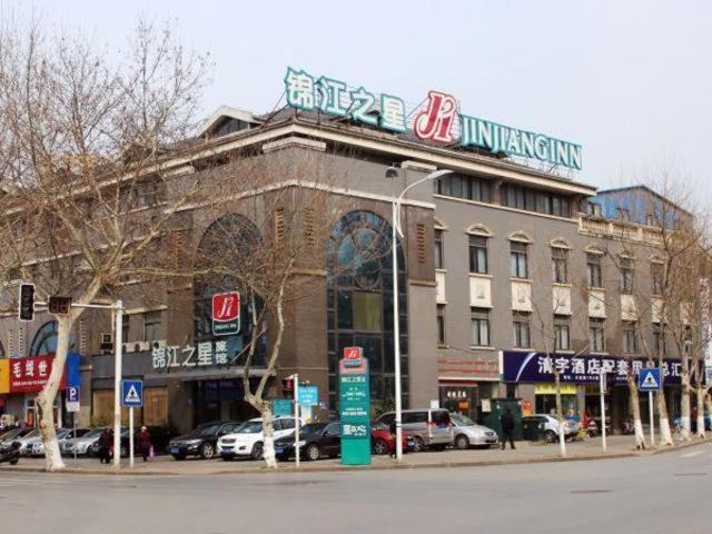 a building on a street with cars parked in front of it at Jingjiang Inn Zhenjiang North Huangshan Road in Zhenjiang