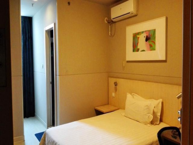 um quarto com uma cama branca e uma fotografia na parede em Jinjiang Inn Xuzhou Golden Eagle International Shopping Center Jiahe East Street Hotel em Xuzhou