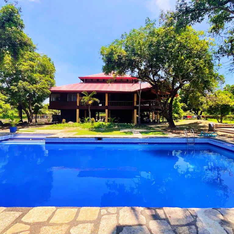 a house with a blue swimming pool in front of a building at RiverCoves Resorts in Bulakan