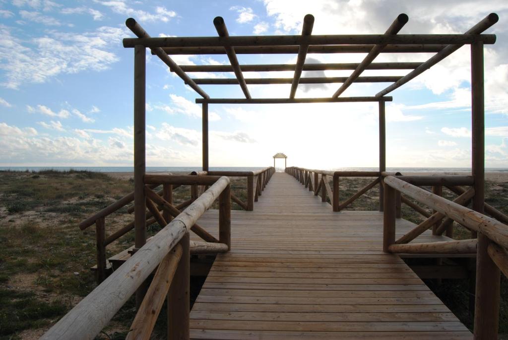 a wooden boardwalk leading to the beach at Casa Entre Armonías in Zahara de los Atunes