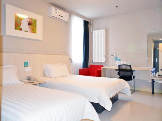 a hospital room with two beds and a red chair at Jinjiang Inn Panjin Shiyou Avenue in Panjin