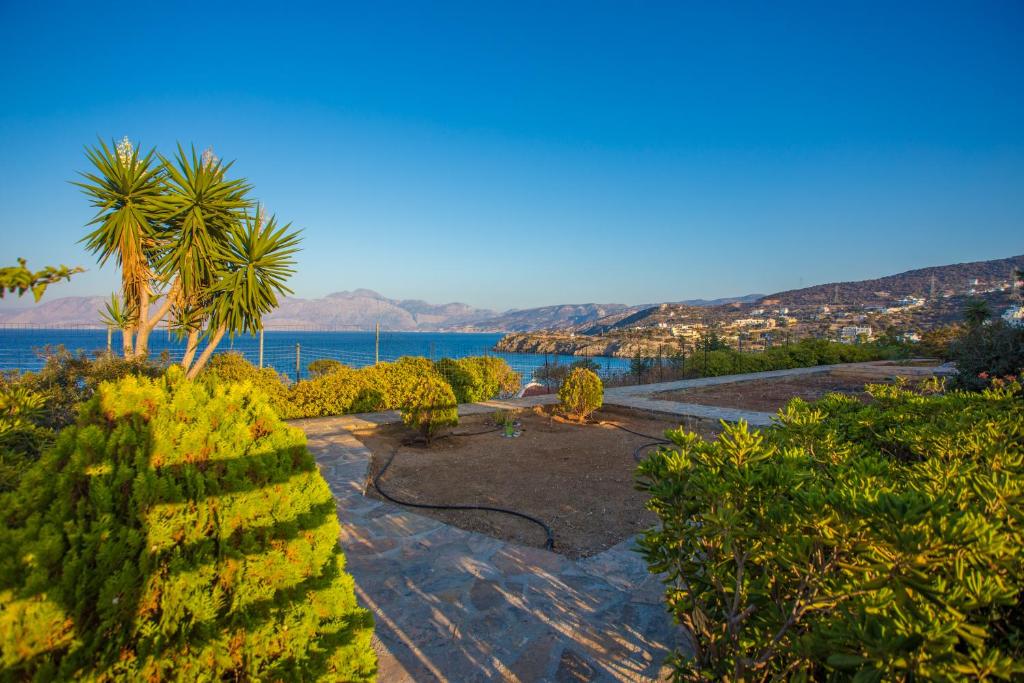 a park with a palm tree and a body of water at Villa Thea in Agios Nikolaos