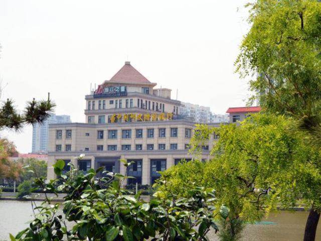 ein großes weißes Gebäude mit einem Turm darüber in der Unterkunft Jinjiang Inn Weihai Shandong University in Weihai