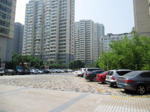 a parking lot with cars parked in front of tall buildings at Jinjiang Inn Luoyang Nanchang Road Wangfujing in Luoyang