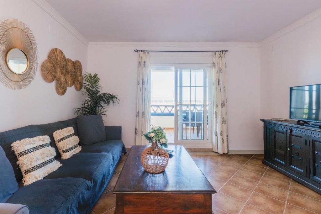a living room with a blue couch and a table at Vista Marina de Isla Canela in Isla del Moral