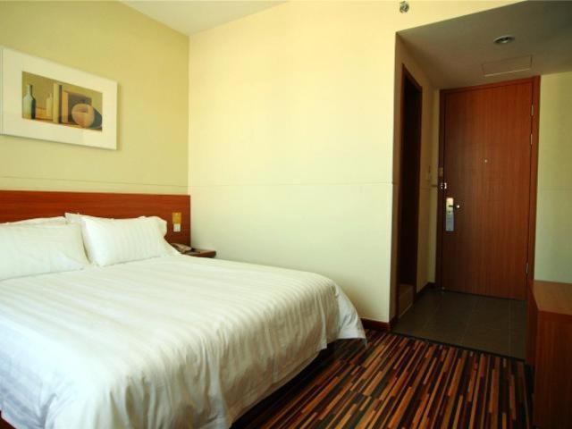 1 dormitorio con cama blanca y puerta de madera en Jinjiang Inn Select Yantai Penglaige en Penglai