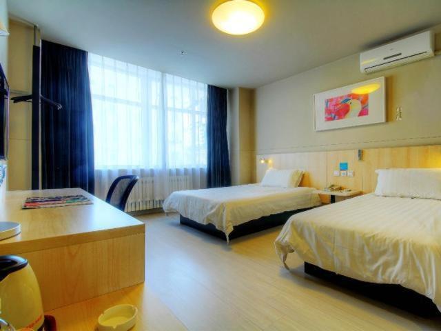 Una habitación de hotel con dos camas y un escritorio. en Jinjiang Inn Liaoning Chaoyang Railway Station, en Chaoyang