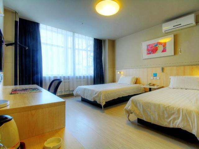 a hotel room with two beds and a desk at Jinjiang Inn Liaoning Chaoyang Railway Station in Chaoyang