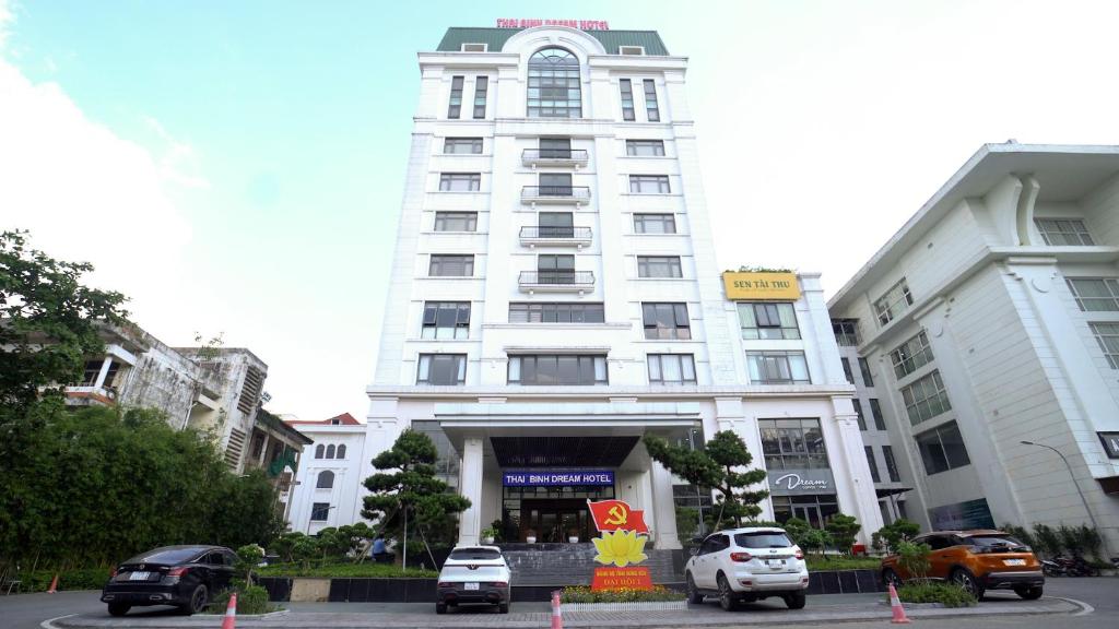 a white building with cars parked in front of it at Khách sạn Thái Bình Dream in Thái Bình