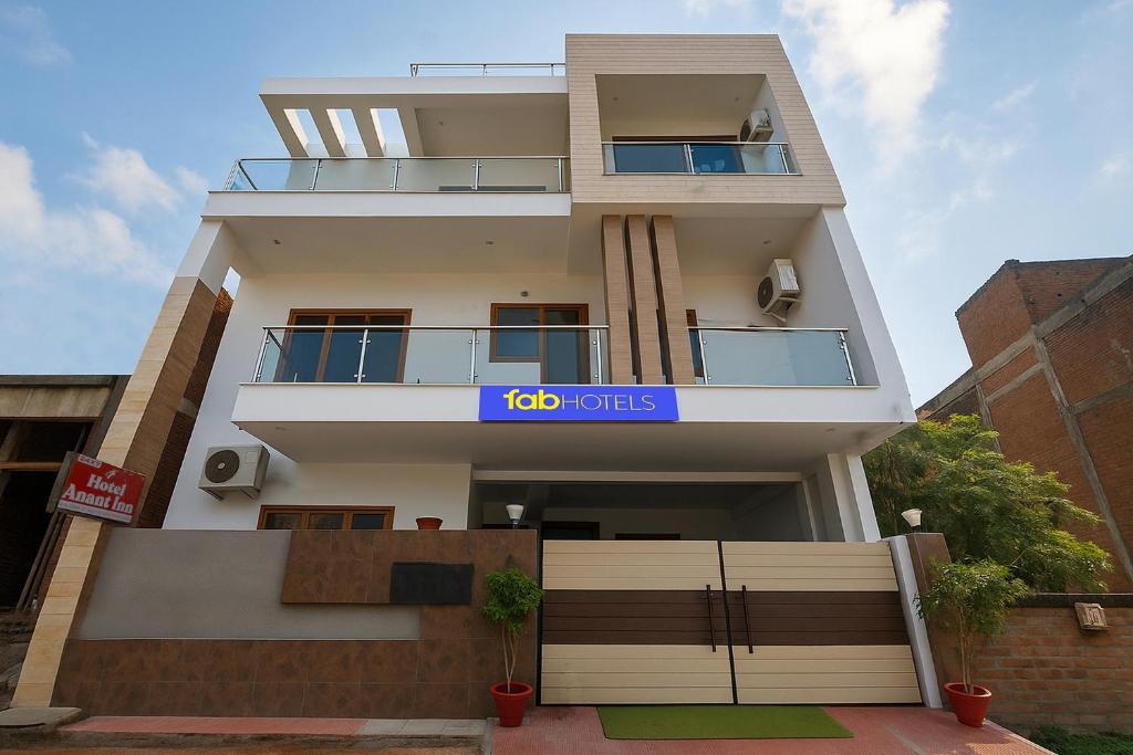 a tall white building with a blue sign on it at FabHotel Anant Inn in Lucknow