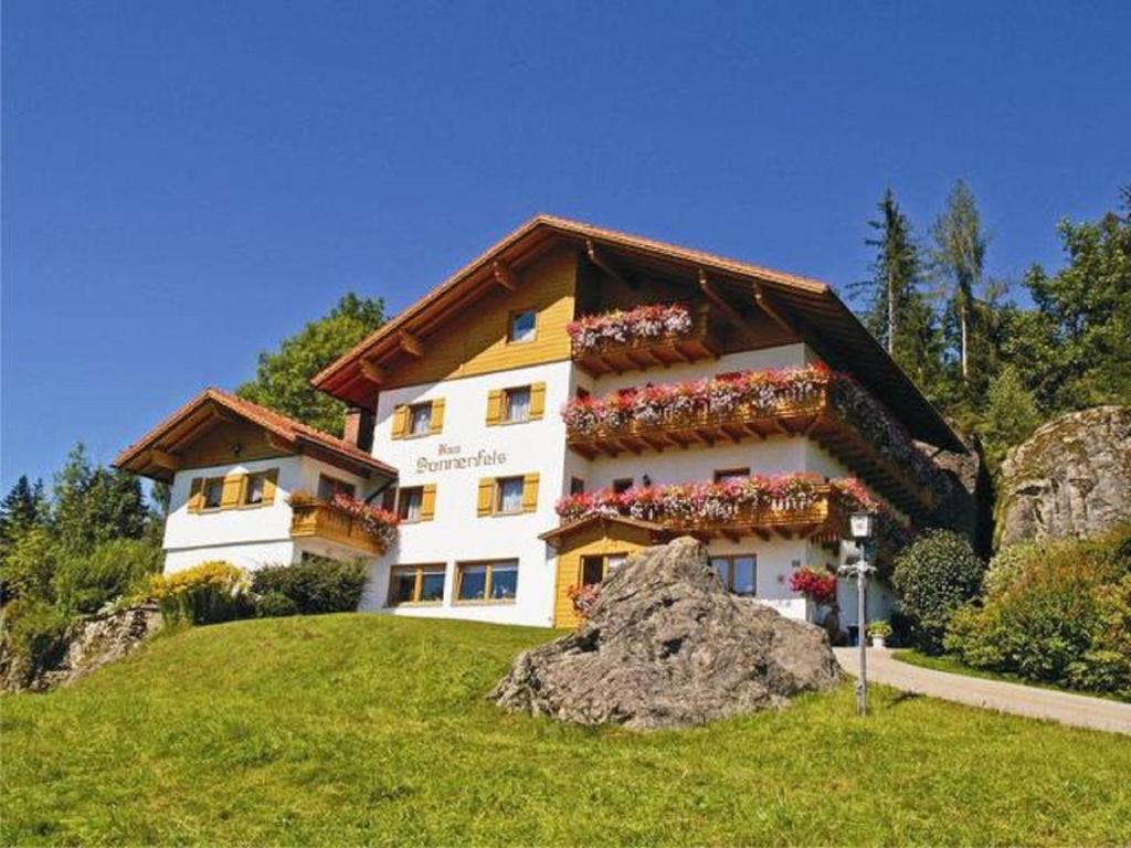 ein Gebäude auf einem Hügel mit Blumen darauf in der Unterkunft Pension Haus Sonnenfels in Bodenmais