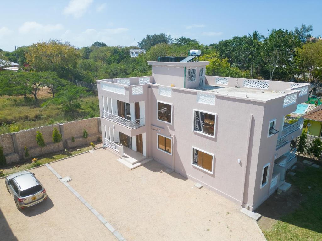 a white house with a car parked in front of it at Jamii Villas Diani in Kwale
