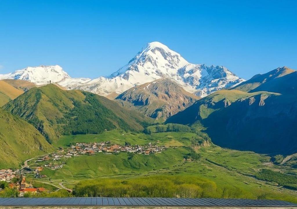 a mountain range with a town in front of a village at Misty Valley in Stepantsminda