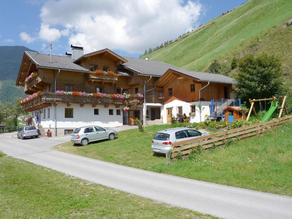 a house on a hill with cars parked in front of it at Apartmenthaus Gutwenger in Innervillgraten