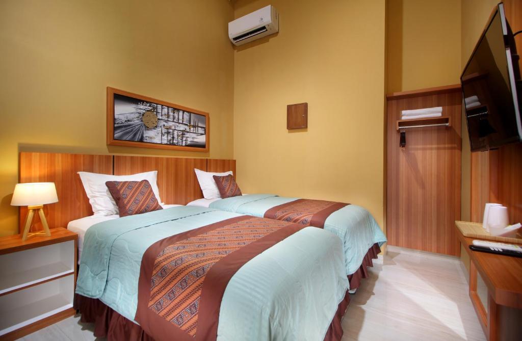 ein Hotelzimmer mit zwei Betten und einem Fernseher in der Unterkunft Family & Superior Hotel Malioboro-Yogyakarta in Sentool