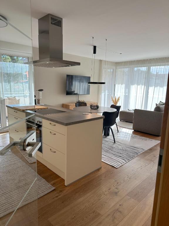 a kitchen with a island in the middle of a living room at "FOUR" - Premium Apartments Seekirchen, Stilvolle 3-Zimmer Wohnung mit Balkon in Größing