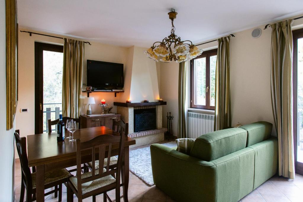 ein Wohnzimmer mit einem Tisch und einer grünen Couch in der Unterkunft La Dimora San Rocco, Montagna e Relax in Roccaraso